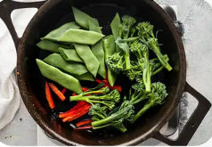 Snap peas, broccolini and red peppers in a cast-iron pan